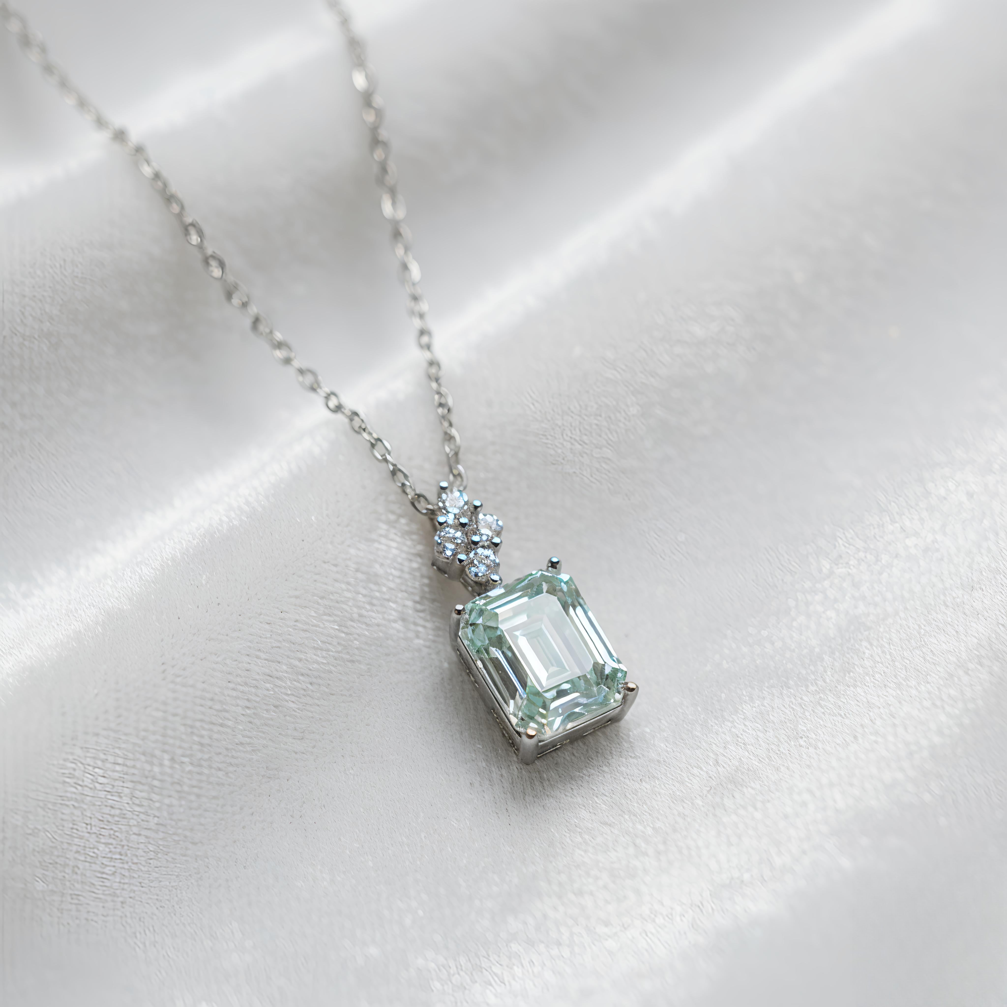 Necklace with a green gemstone pendant on a white satin background