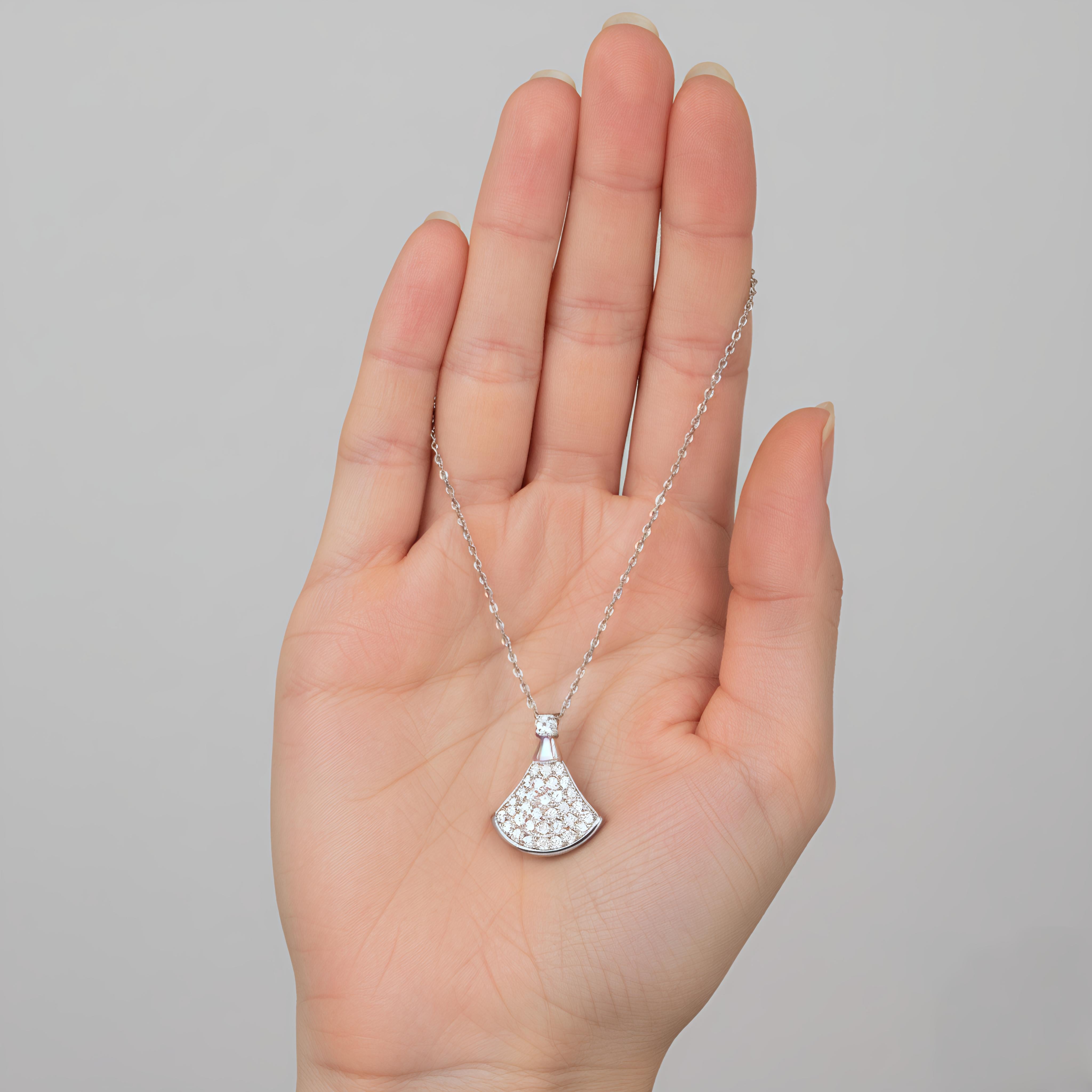 Silver necklace with a diamond pendant held in a hand against a gray background
